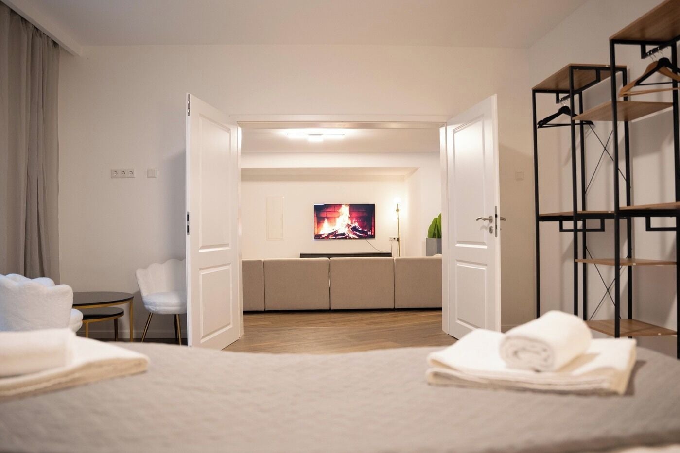 A hotel room with a bed, a seating area with a TV, and a wardrobe.