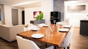 Un comedor moderno con una mesa de madera preparada para seis personas, rodeada de sillas blancas.