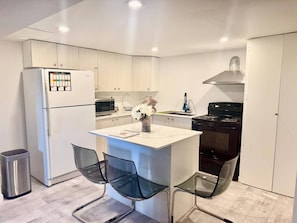 A modern kitchen with a central island, stainless steel appliances, and glass chairs.