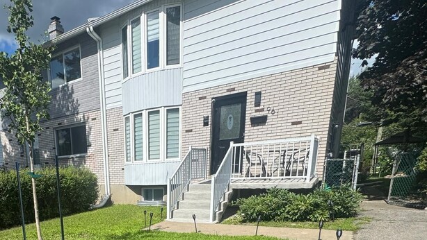 A two-story building with a brick facade, a front entrance with a set of stairs, and a well-maintained lawn.