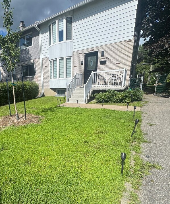 A two-story building with a brick facade, a front entrance with a set of stairs, and a well-maintained lawn.