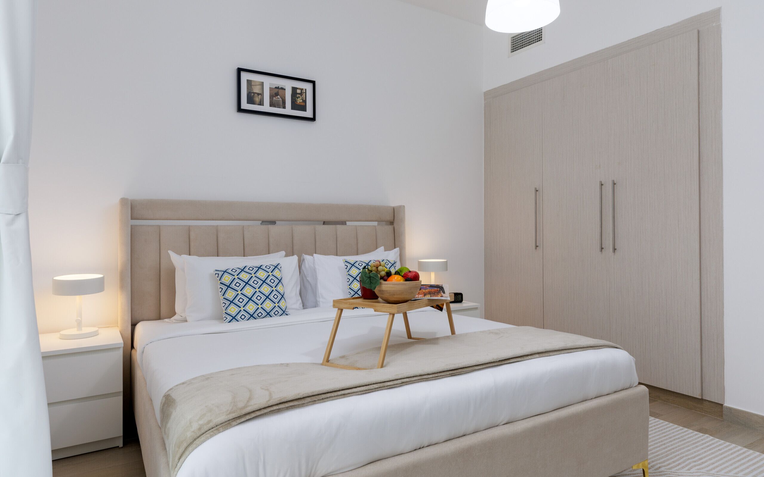 Un dormitorio con cama, mesitas de noche, armario y un cuadro en la pared.