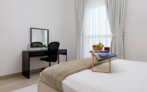 Een moderne hotelkamer met een bed, een bureau, een stoel, een spiegel en een raam met gordijnen.