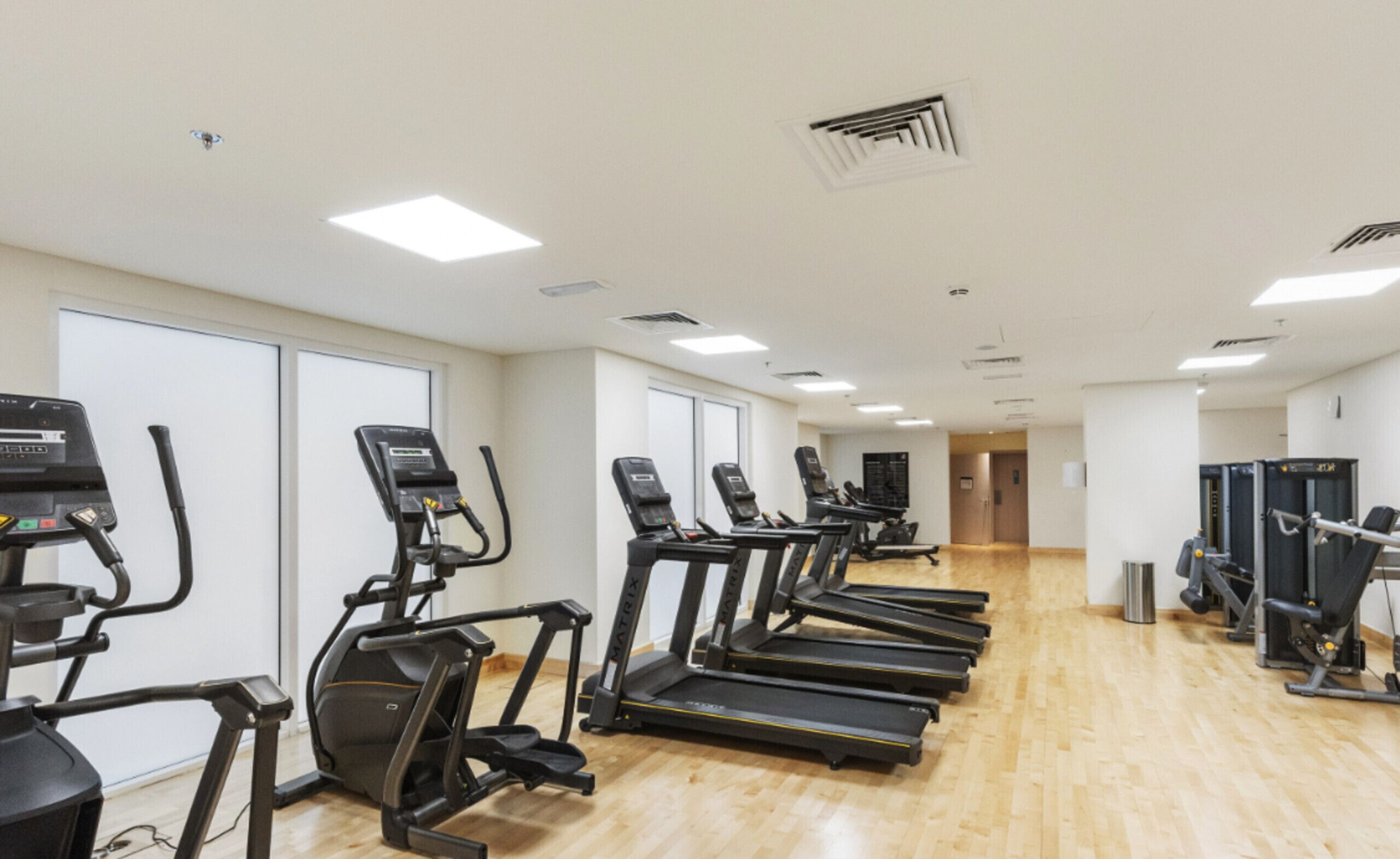 Ein Fitnessstudio mit Laufbändern, Crosstrainern und Gewichten.