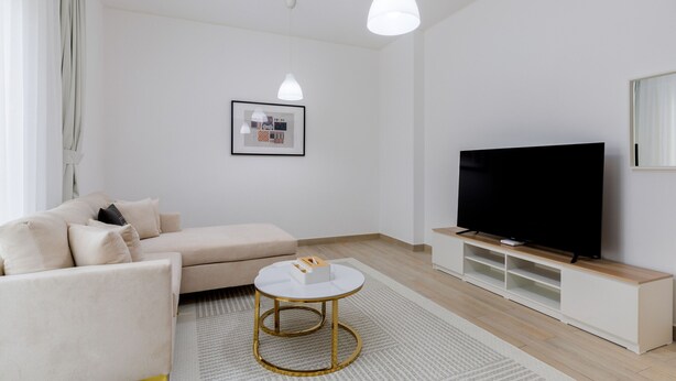 Een moderne woonkamer met een bank, salontafel, televisie en hanglampen.