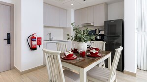 Een moderne keuken met witte kastjes, een zwarte koelkast en een eettafel gedekt met rode servies en glazen.
