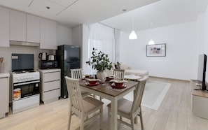 Een moderne keuken met een eethoek, voorzien van een kookplaat, magnetron, koelkast en een voor vier personen gedekte eettafel.