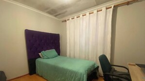 A small, single-bed room with a purple headboard, a green bedspread, a black office chair, and a wooden desk. - Spacious House Rental with Private Rooms in Cape Town (Cape Town)