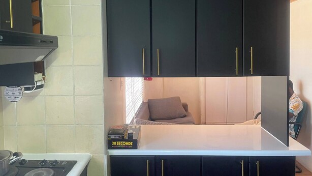 A compact kitchenette with a stove, a small countertop, and a black cabinet with gold handles. - Spacious House Rental with Private Rooms in Cape Town (Cape Town)
