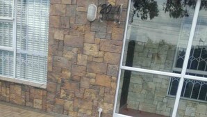 A building with a stone facade, a large glass window, and a brick-paved ground. - Spacious House Rental with Private Rooms in Cape Town (Cape Town)