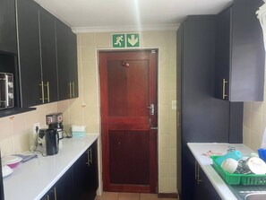 Een kleine keuken met donkere kastjes, een koffiezetapparaat en een gootsteen.