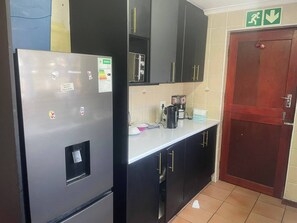 Een keuken met een koelkast, een koffiezetapparaat en kastjes.