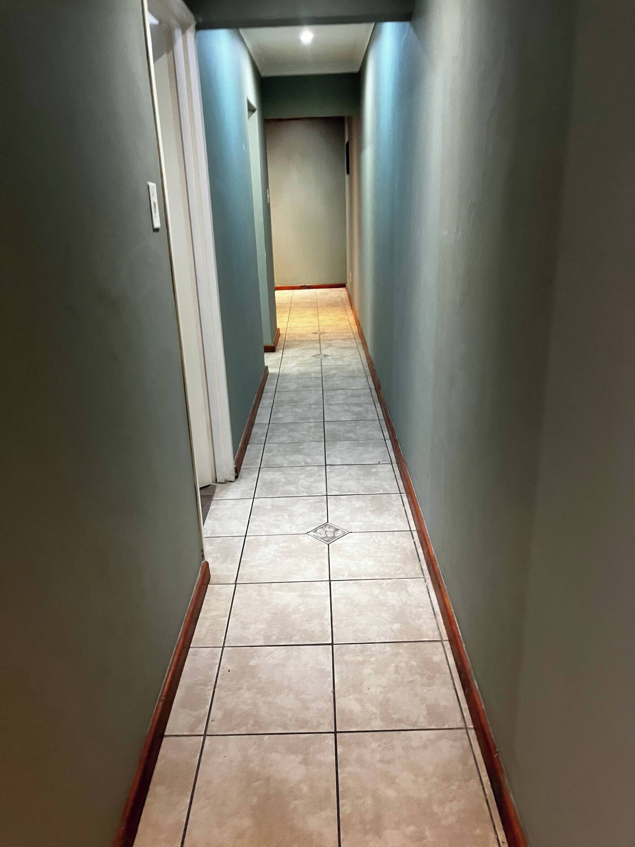 Un pasillo estrecho con paredes azul claro y piso de baldosas.