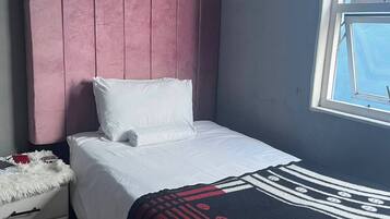 Una camera da letto con un letto, un comodino, una finestra e una testiera.