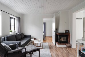 A modern living room with a grey sofa, a small round table, and a fireplace.