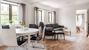 Ett modernt vardagsrum med en matplats, stora fönster och utsikt över grönområden utanför.