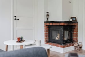 A room with a fireplace, a white door, and a small table with a cup and a decorative item. - Linneby , fri parkering (Uddevalla)