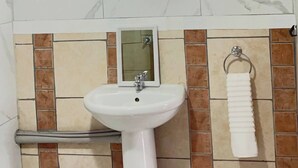 A bathroom with a white pedestal sink, a mirror, and a towel rack.