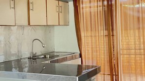 A kitchen with a marble countertop, a sink, and cabinets.