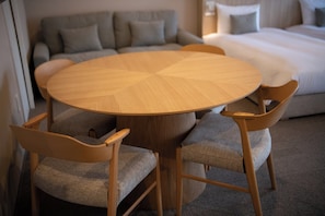 Une table ronde en bois, entourée de quatre chaises, dans une chambre d’hôtel.