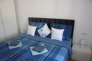A bed with a blue and white checkered bedspread, two pillows with a butterfly design, and two folded towels on the bed. - Apartment Dino, Zadar - Charming Fully Furnished 2-Bedroom with AC (Zadar)