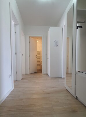 A hallway with white doors, a white refrigerator, and a wooden floor. - Apartment Dino, Zadar - Charming Fully Furnished 2-Bedroom with AC (Zadar)
