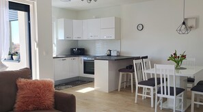 A modern kitchen with white cabinets, a dining area with white chairs, and a clock on the wall. - Apartment Dino, Zadar - Charming Fully Furnished 2-Bedroom with AC (Zadar)