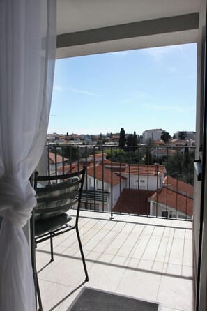 A balcony with a chair and a view of a residential area. - Apartment Dino, Zadar - Charming Fully Furnished 2-Bedroom with AC (Zadar)