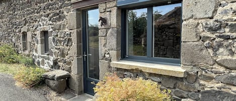 Un bâtiment en pierre avec une porte sombre, des fenêtres et un rebord en pierre.