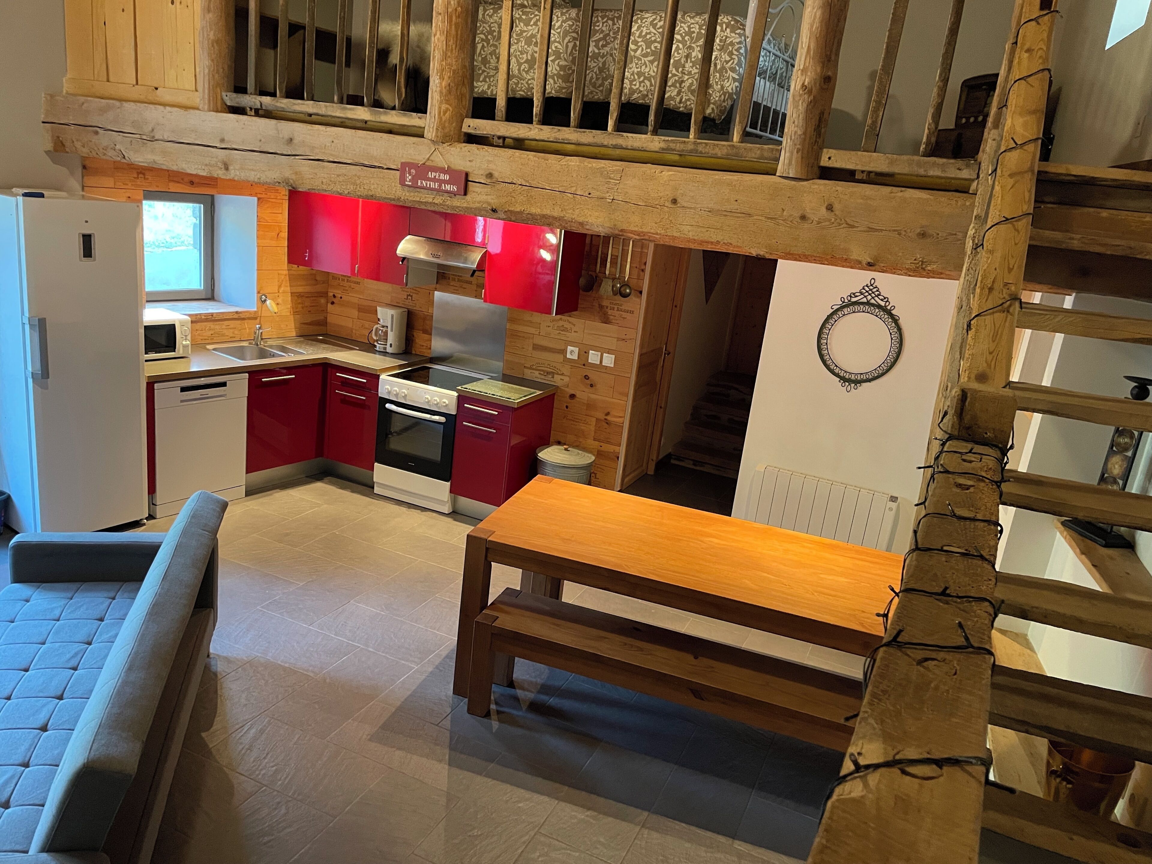 A kitchen with red cabinets, a wooden table, and a staircase leading to a loft area.