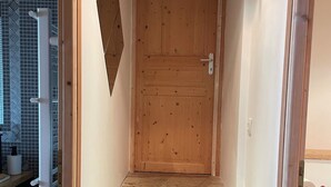 A wooden door with a metal handle, leading to a staircase with stone steps.