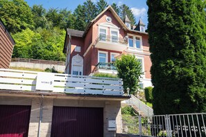 Ein zweistöckiges Haus mit Balkon, Garage und Zaun.