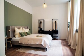 Ein modernes Schlafzimmer mit Bett, Nachttischen, einem Kleiderschrank und einer Pendelleuchte.