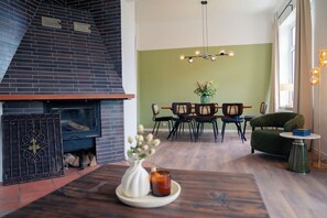 Ein modernes Wohnzimmer mit Kamin, Essbereich und einer grünen Wand.