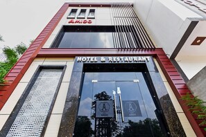 A hotel entrance with a sign reading 'AMIGO HOTEL & RESTAURANT' and a logo with a stylized 'A'.