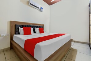 A bed with a wooden headboard, white bedding, and red accents.
