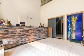 A reception area with a modern counter, a 'No Smoking' sign, and a glass door leading to an office.