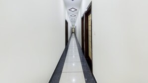 Un pasillo con piso de baldosas, paredes blancas y una puerta a la derecha.
