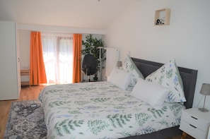 A bedroom with a bed, a desk, a chair, and a plant. - Cozy apartment with a kitchen for couples and families (München)