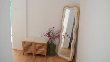 A room with a wooden bench, a large mirror with a wooden frame, and a vase with red berries.