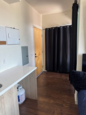 A room with a wooden floor, a white desk, a black curtain, and a door. - Modern Studio with balcony in the center of Hollywood Walk of Fame area (Los Angeles)