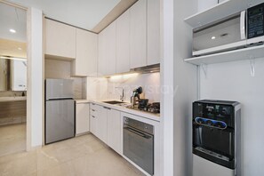 A modern kitchen with a built-in oven, a refrigerator, and a water dispenser. - Arova by Kozystay - Cilandak (South Jakarta)