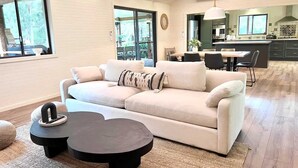 A modern living room with a sofa, two coffee tables, and a dining area with chairs and a table. - Laguna  Farmhouse Studio (Laguna)
