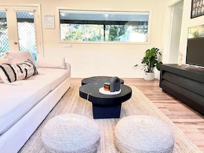 A living room with a sofa, a coffee table, and a television.