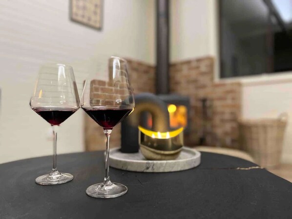 Two wine glasses on a table with a fireplace in the background.