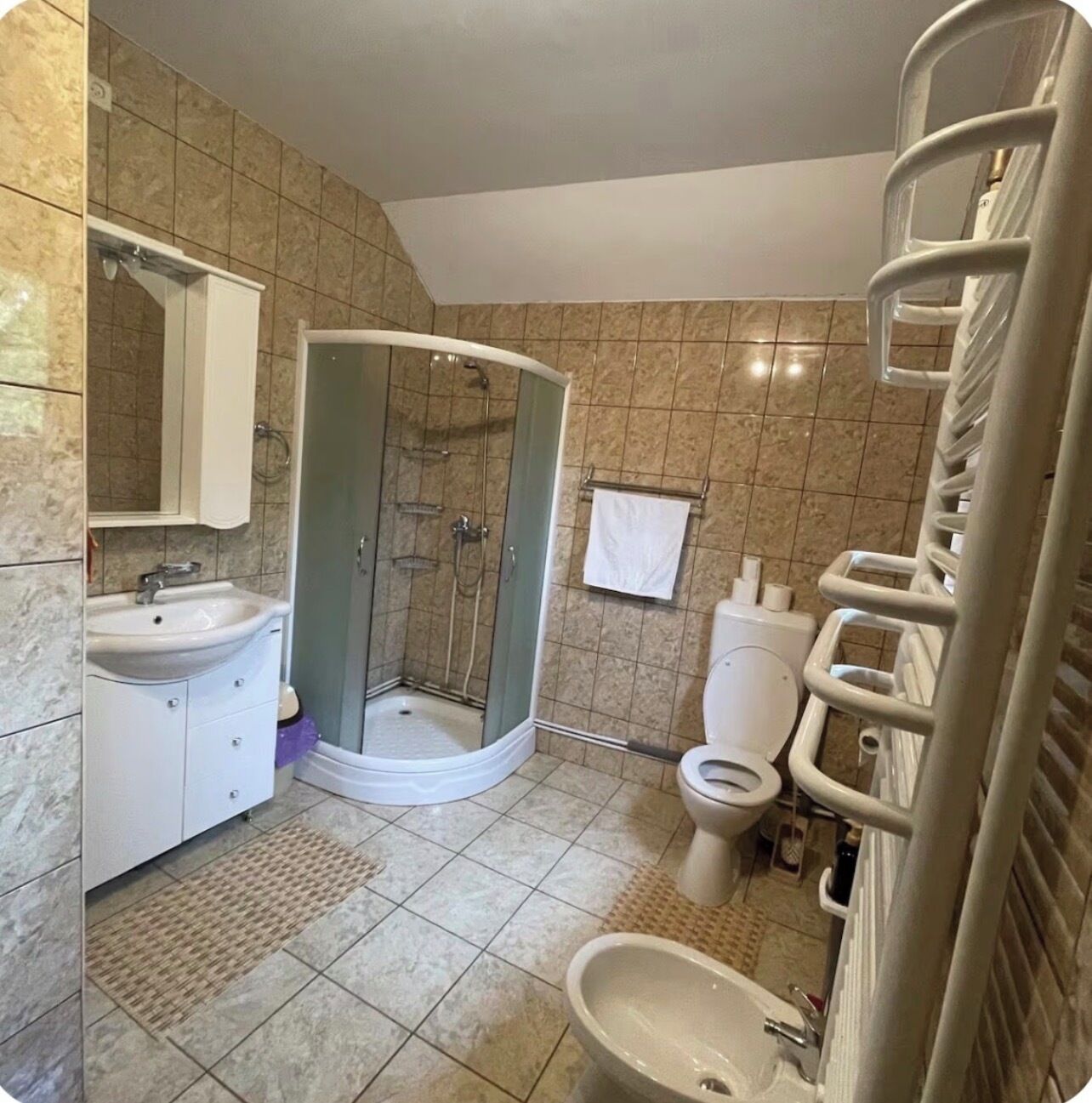 Et badeværelse med brusebad, toilet, bidet og vask.