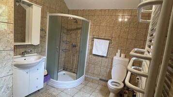 Et badeværelse med brusebad, toilet, bidet og vask.