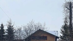 A house with a sloped roof, surrounded by snow-covered ground and leafless trees.