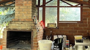 An outdoor kitchen area with a brick oven, a coffee machine, and a window overlooking greenery.