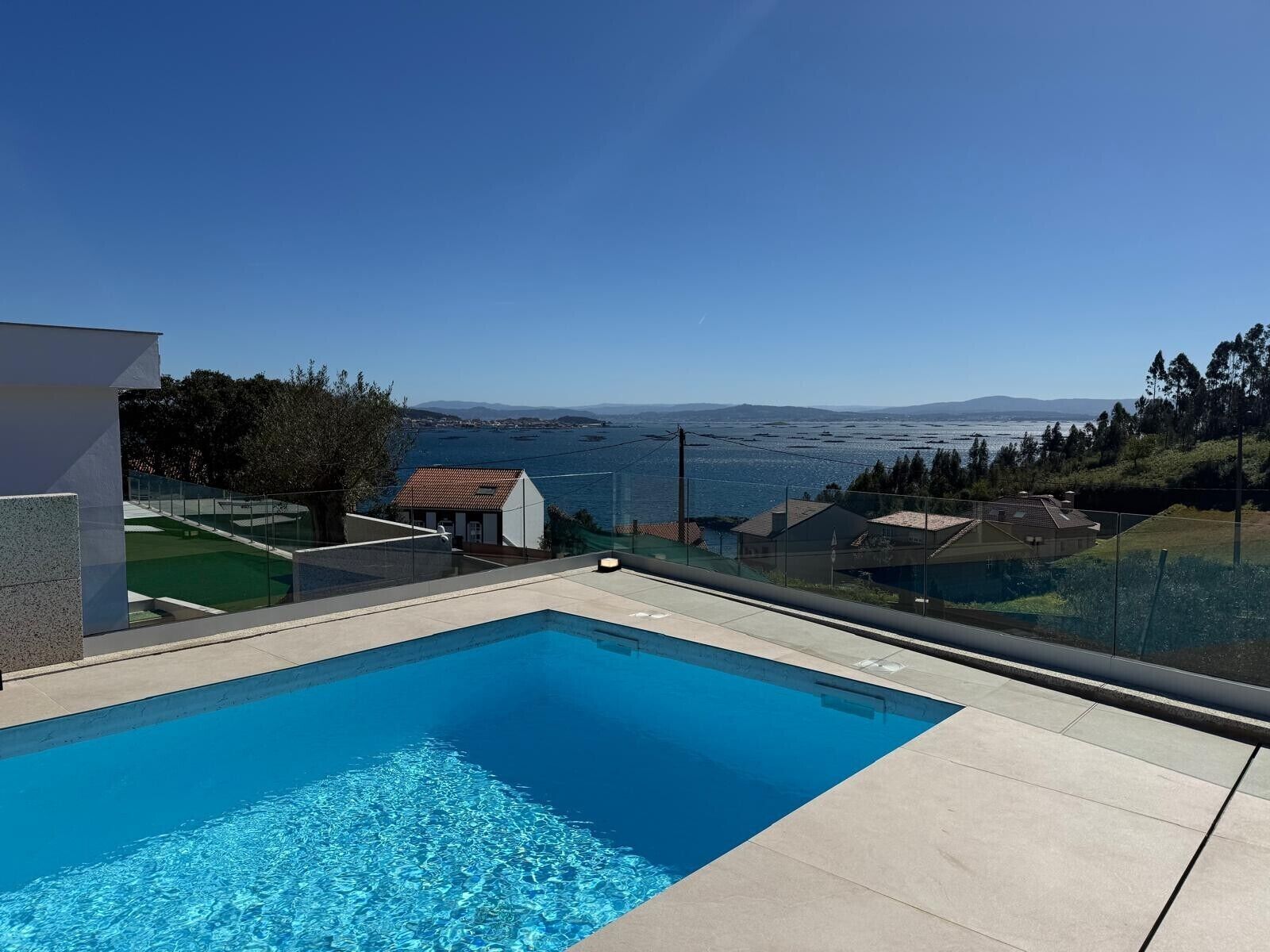 A swimming pool with a clear view of the sea and distant mountains.